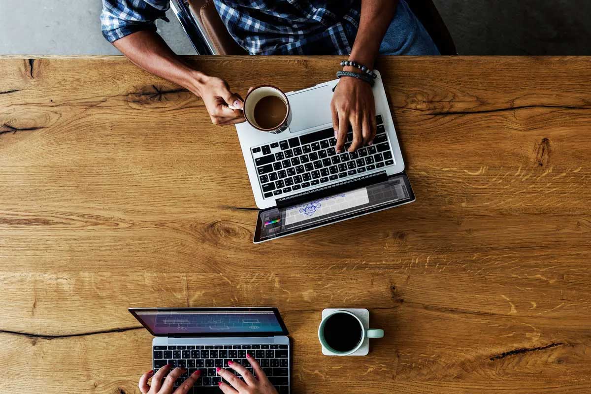 Overhead view of laptops and coffee mugs on wood table